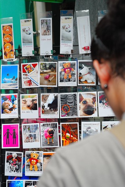 a woman looking at a wall full of post cards