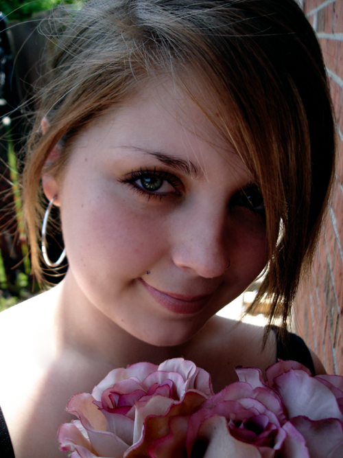 a close up of a person near a brick wall and flower