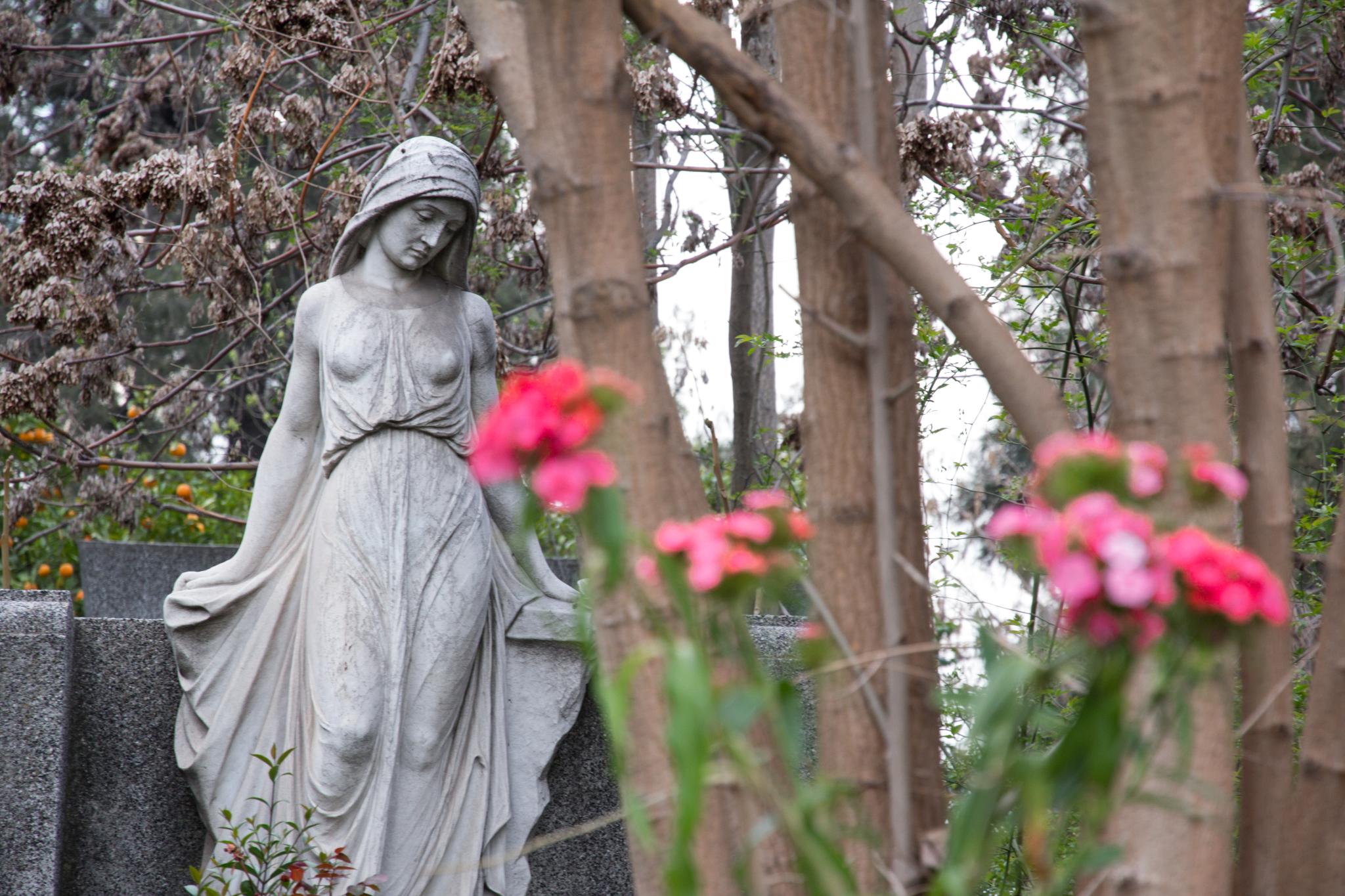 a statue in front of some pink flowers