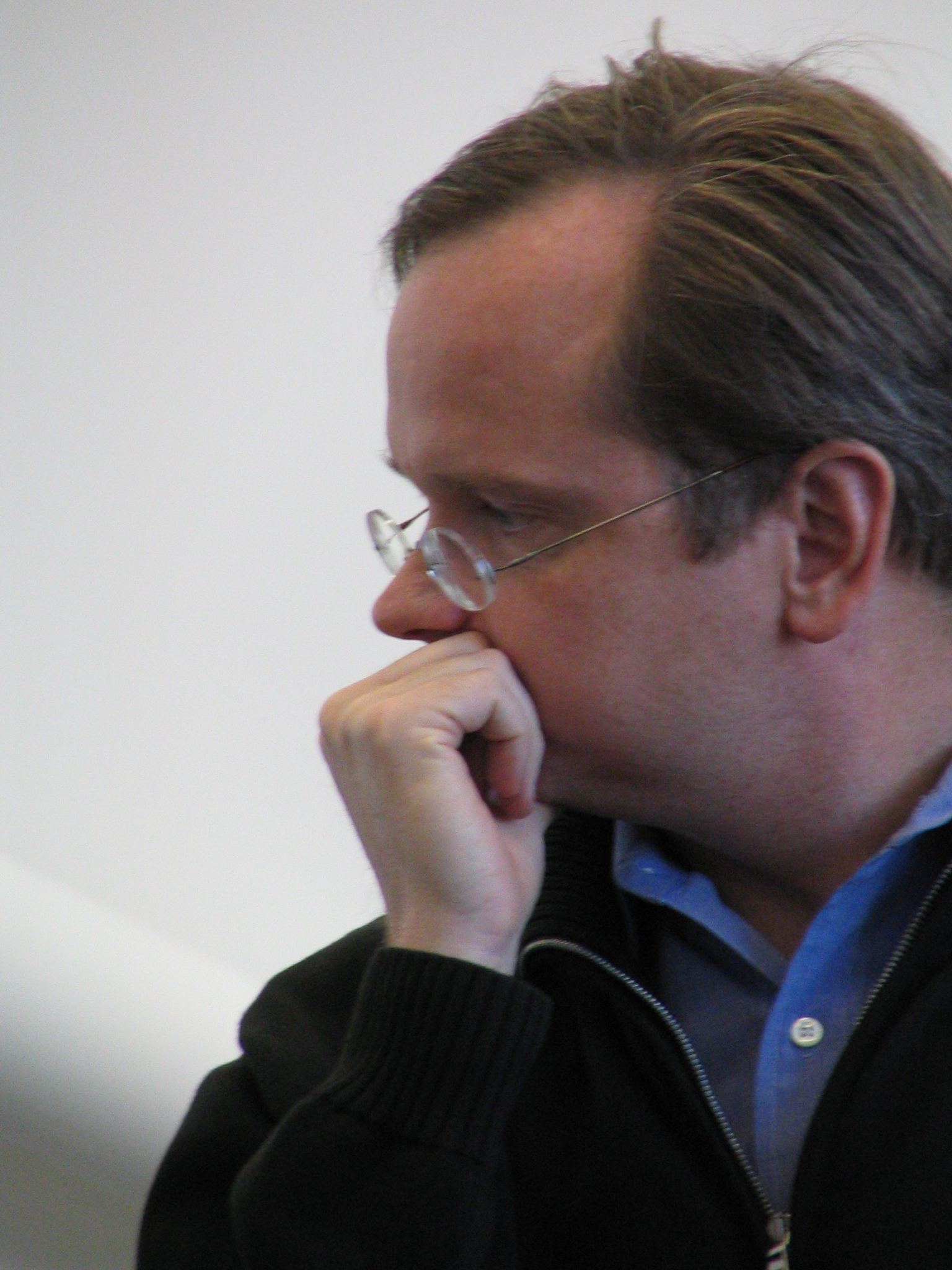 a man in a jacket and glasses stares intently at soing