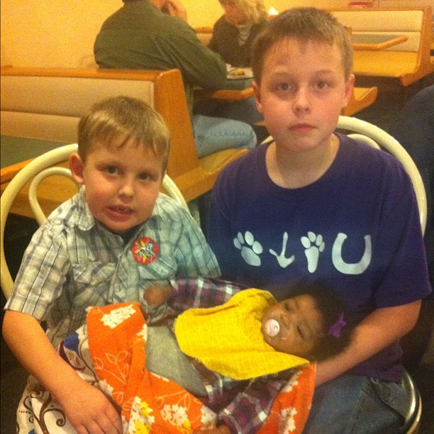 two boys are sitting with a teddy bear