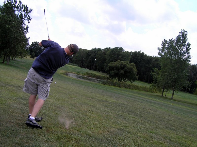 a man standing on a green field holding a golf club