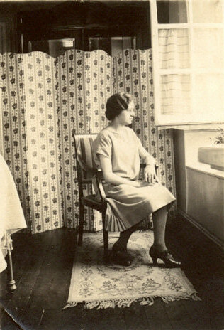 a black and white po of a woman sitting in an old fashioned chair