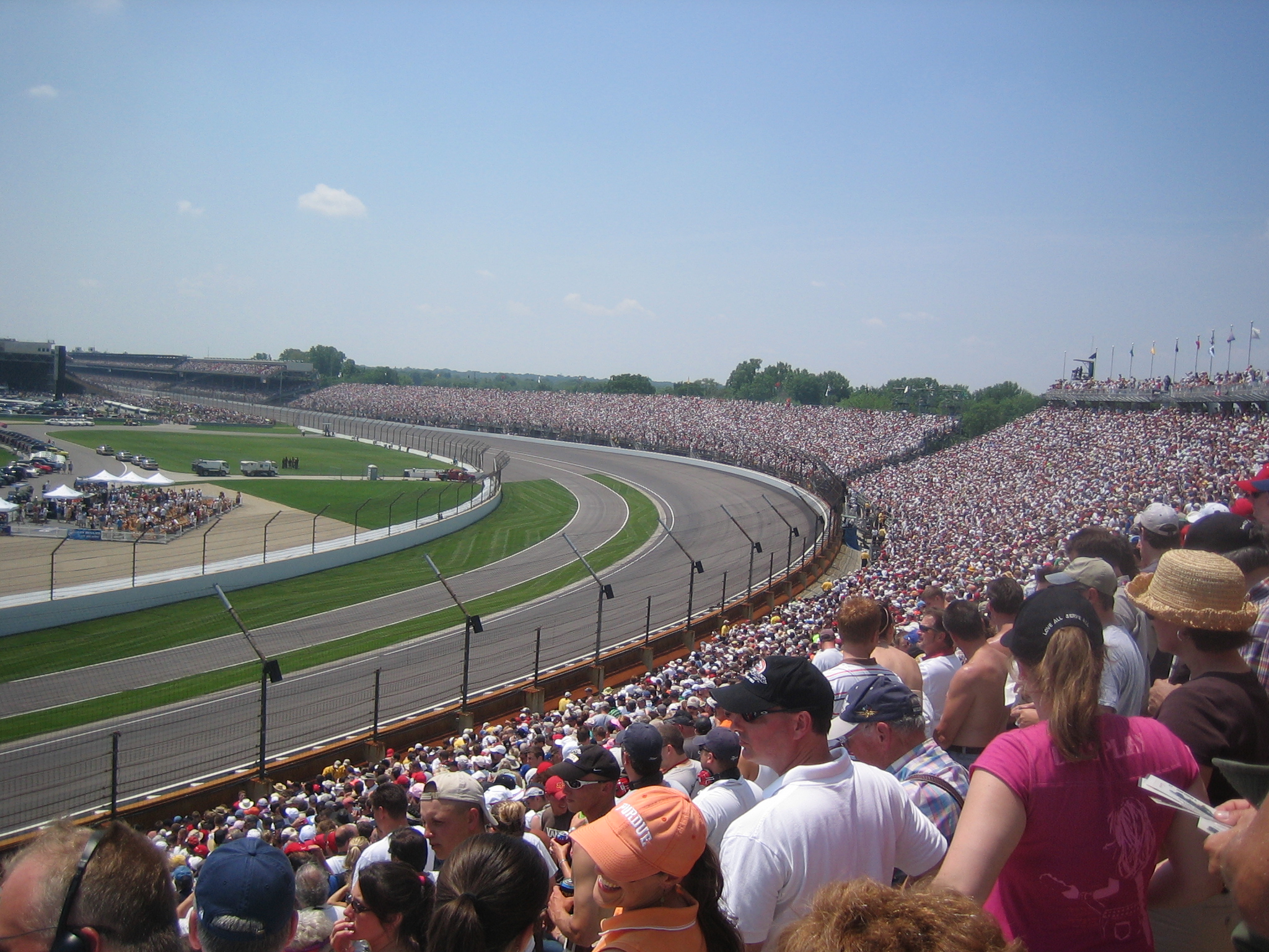 a large group of people stand around an empty race track
