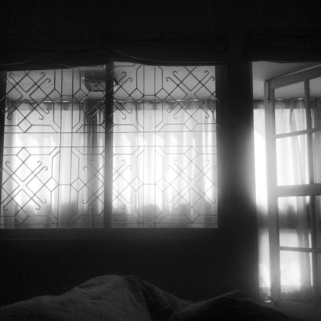 a bed in a dark room with two windows