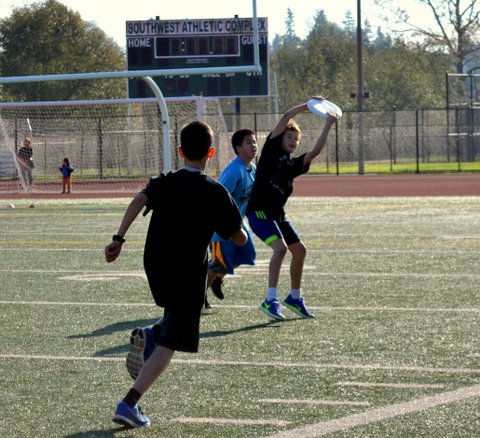 three young men playing a game of frisbee on the field