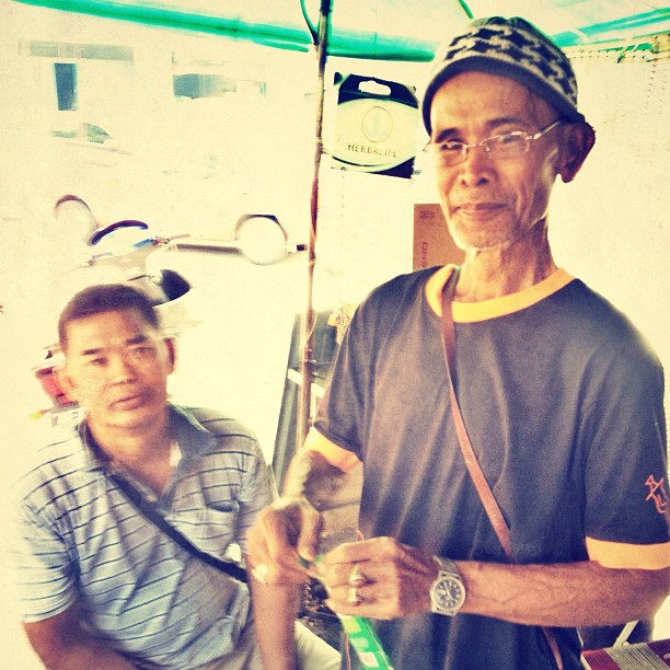 a man holding a fish on a pole next to another person