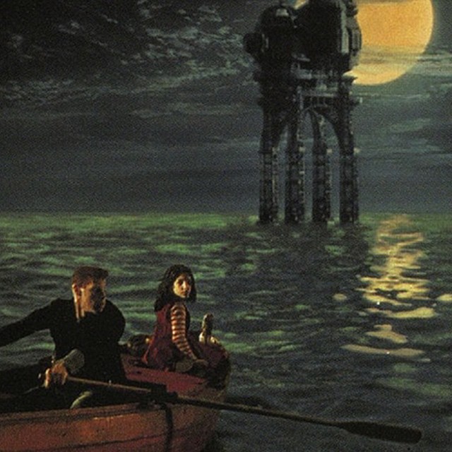 a man and woman sit in the bow of a boat at night while one paddles behind them