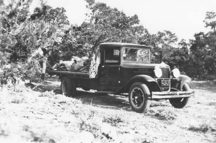 an old black and white po of people in a pickup truck