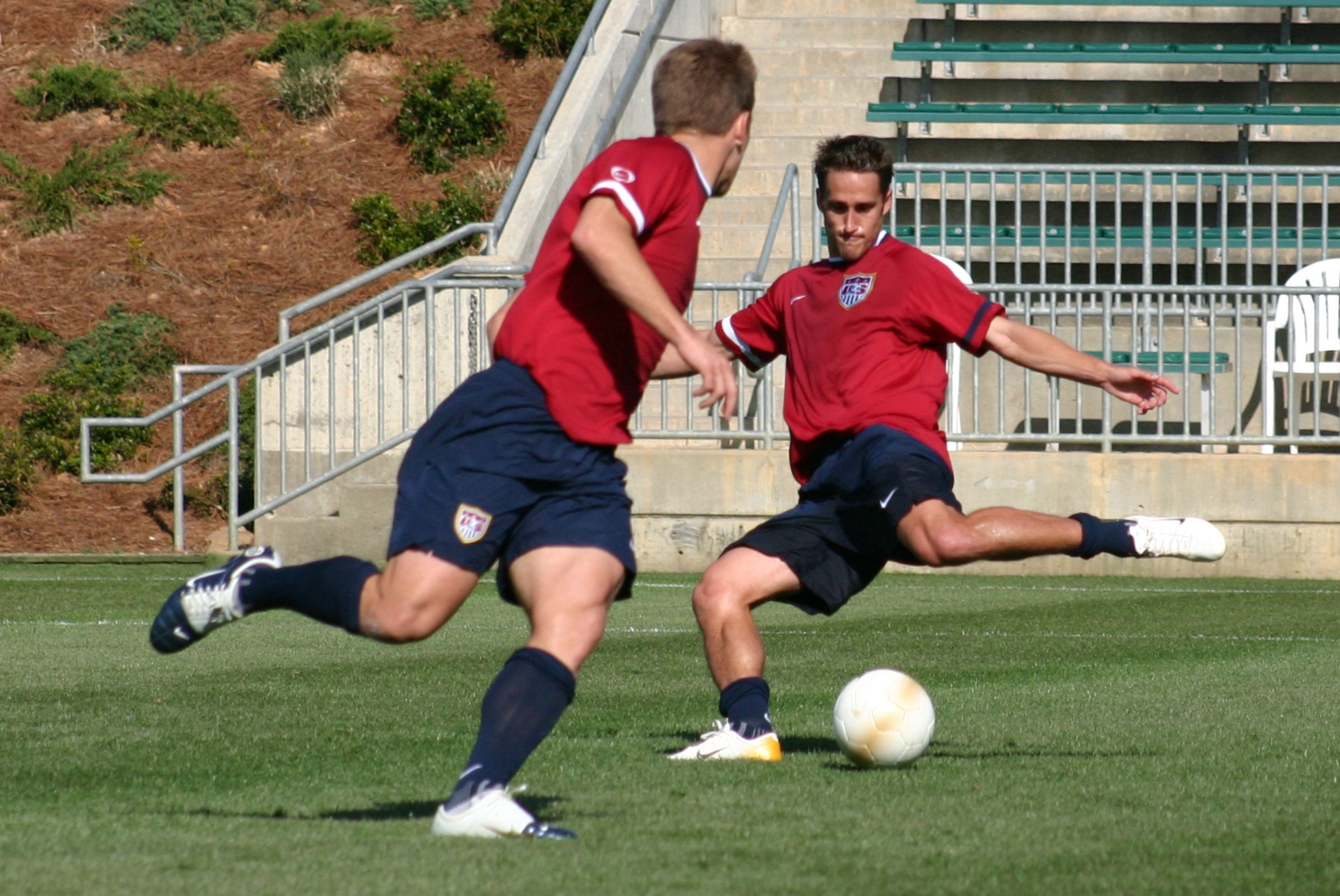 two soccer players kicking a soccer ball across the field