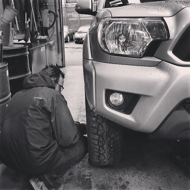 a man fixing his car's hood while working on a lift