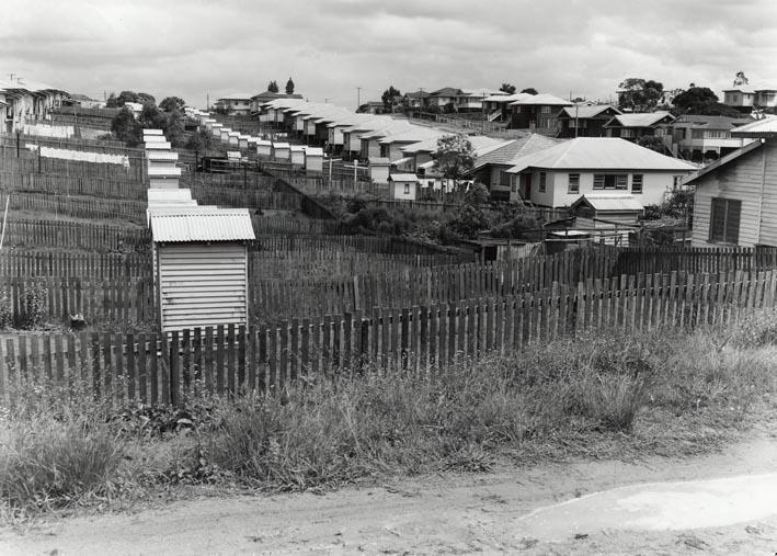 black and white pograph of a village with picket fence and many houses