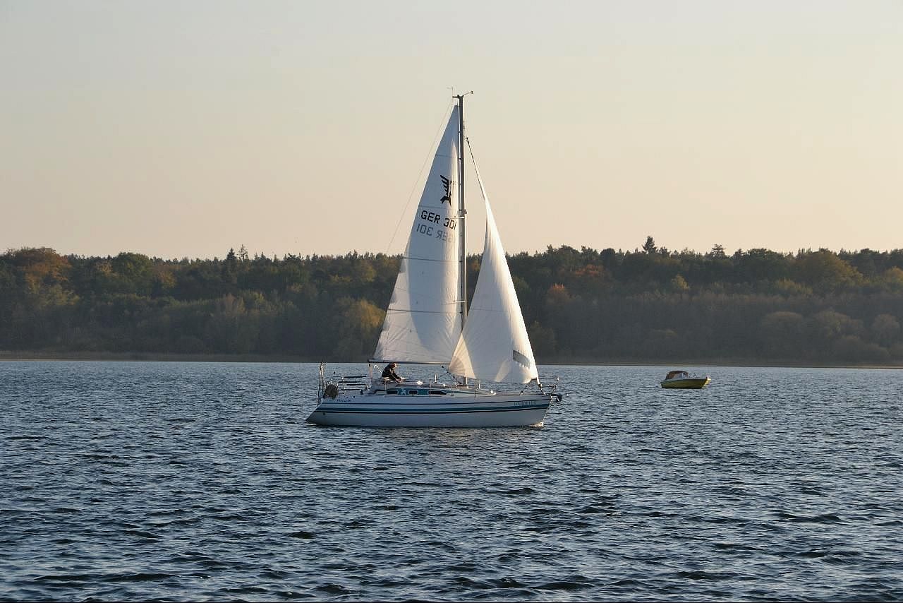 a sailboat and two men on a lake in autumn