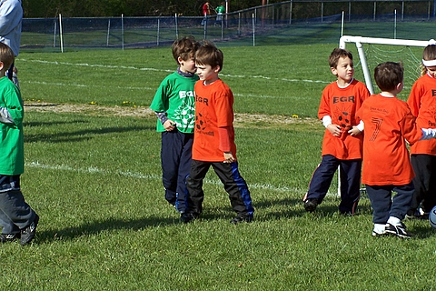 children in green and orange uniforms playing a game