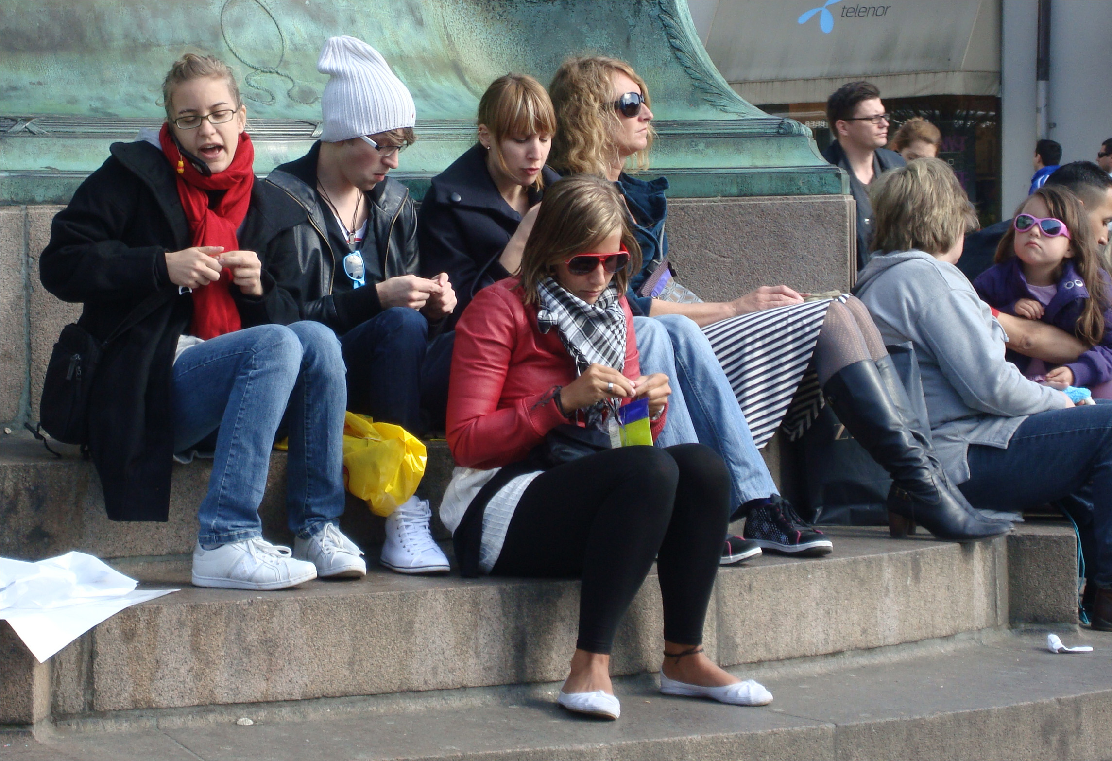 a group of people sitting on the edge of a fountain