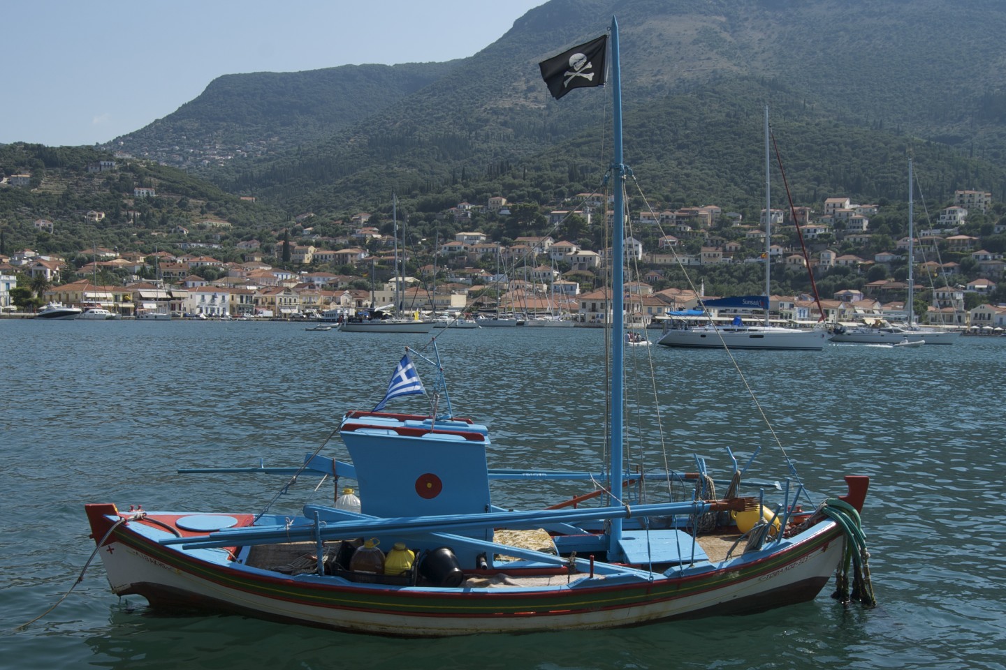 small boat in calm body of water with town in background