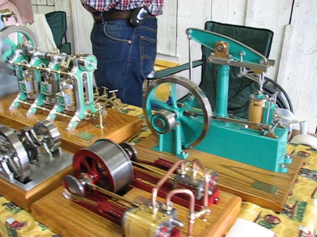 some men stand next to some old fashioned sewing machines