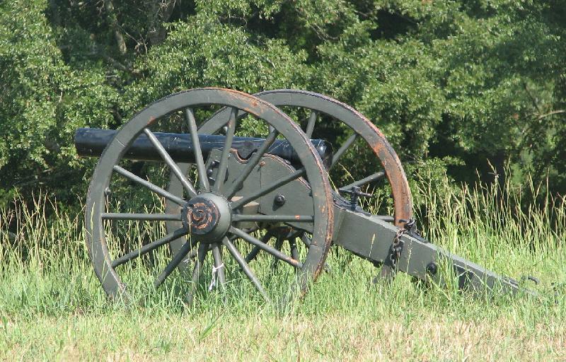 a large gun sitting in some tall grass