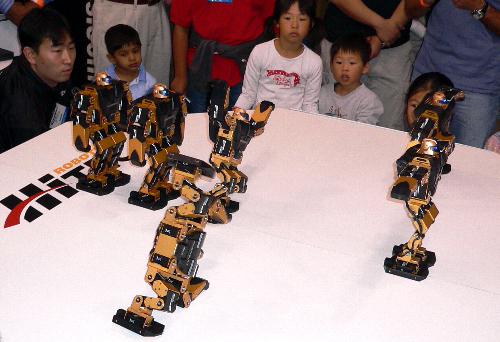 children and adults looking at a small robot sculpture