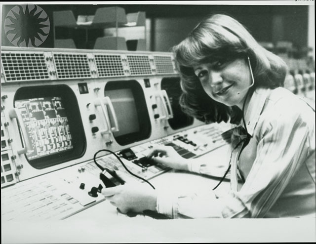 the woman is sitting at the control panel for the computer