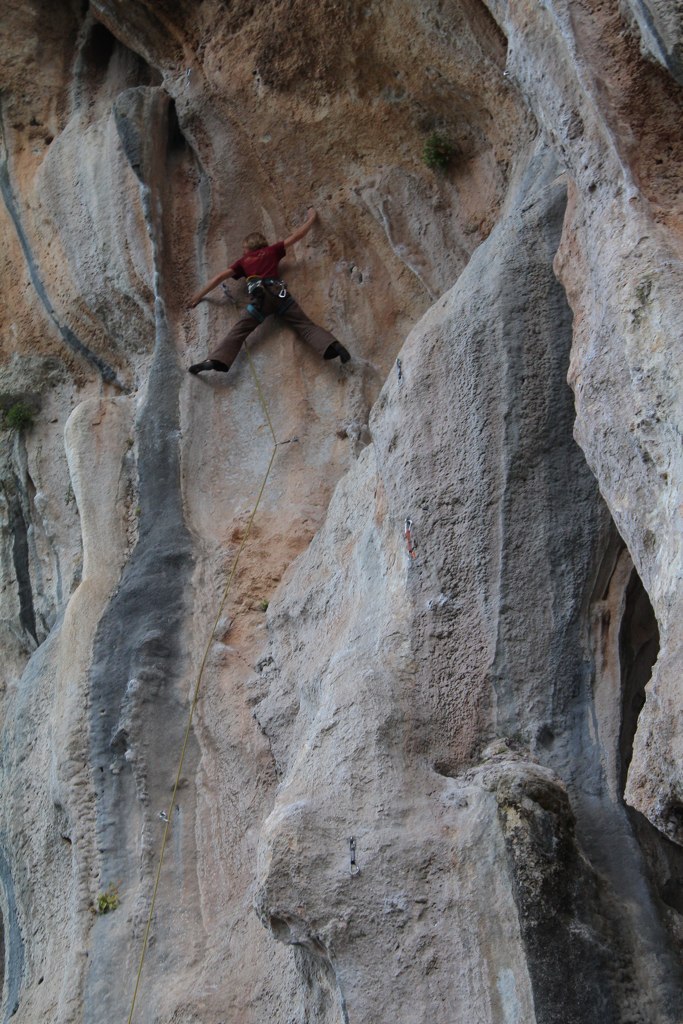 a man climbs along the side of a cliff