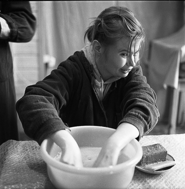 a little girl mixing a bowl of water on a table