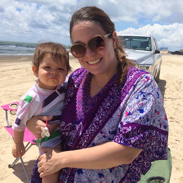 a woman and a baby in purple are on a beach