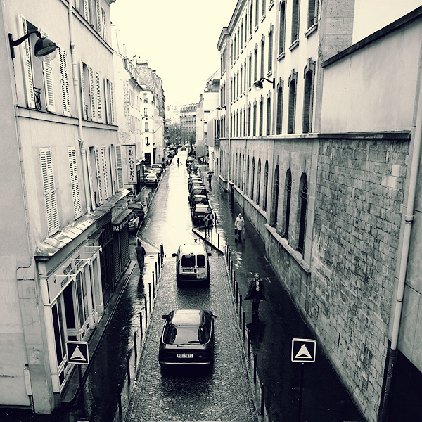a black and white image of parked cars in a narrow street