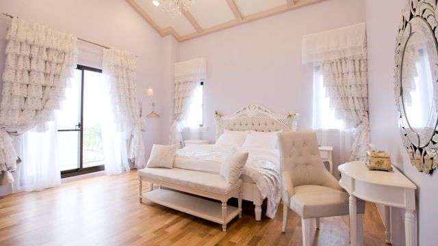 large bedroom with white furniture and a white chair