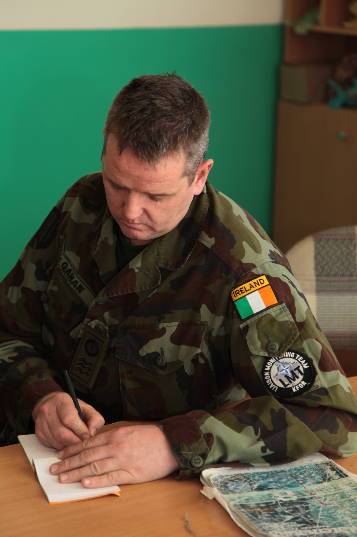 man in military uniform writing on a notepad with a pen