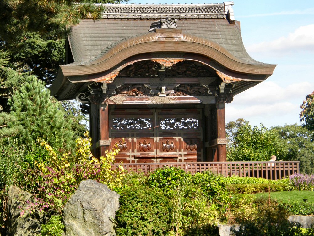 a wooden gate with ornate designs in front of rocks