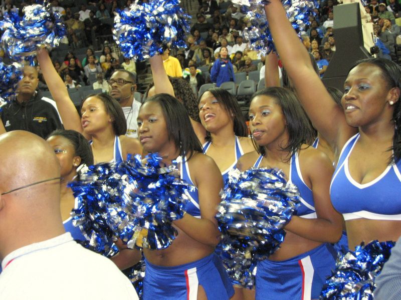 cheerleaders stand together with their poms in front of an audience