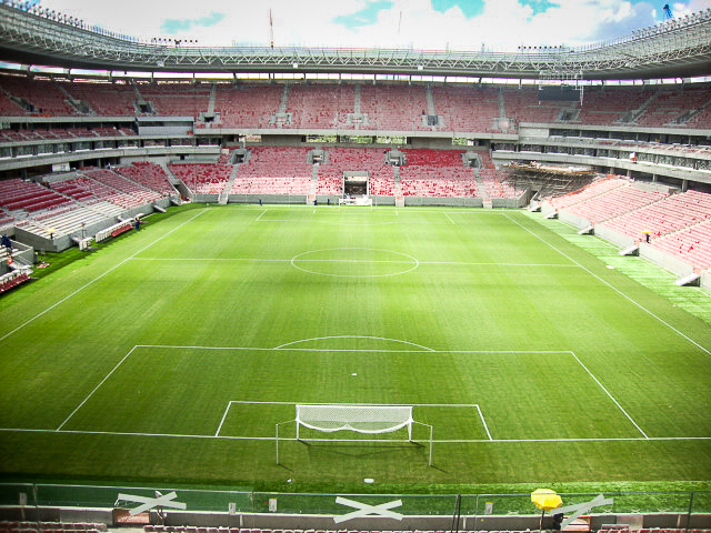 a soccer field with red chairs and empty stands