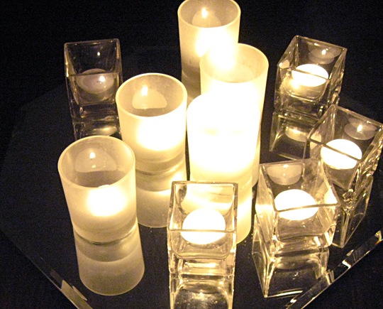many lit candles sit on a glass surface