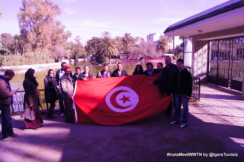 a group of people are holding a flag while others are standing near the water