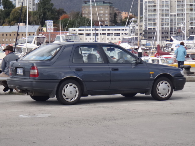 a car sits parked at the dock with several other boats docked