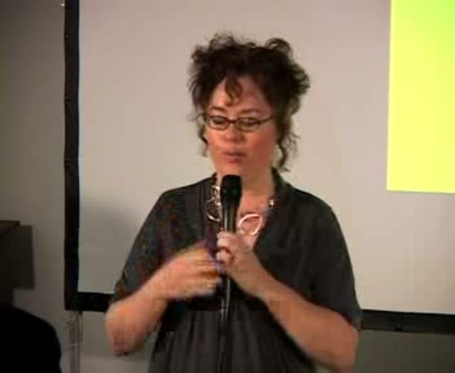 woman holding a microphone while standing in front of a projector screen