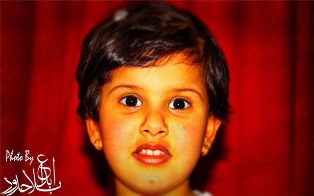a boy stares straight ahead with a red background