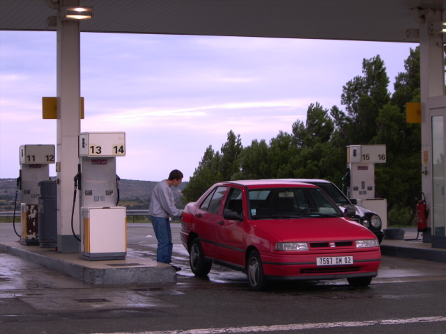 a man at a gas station giving fuel to his car