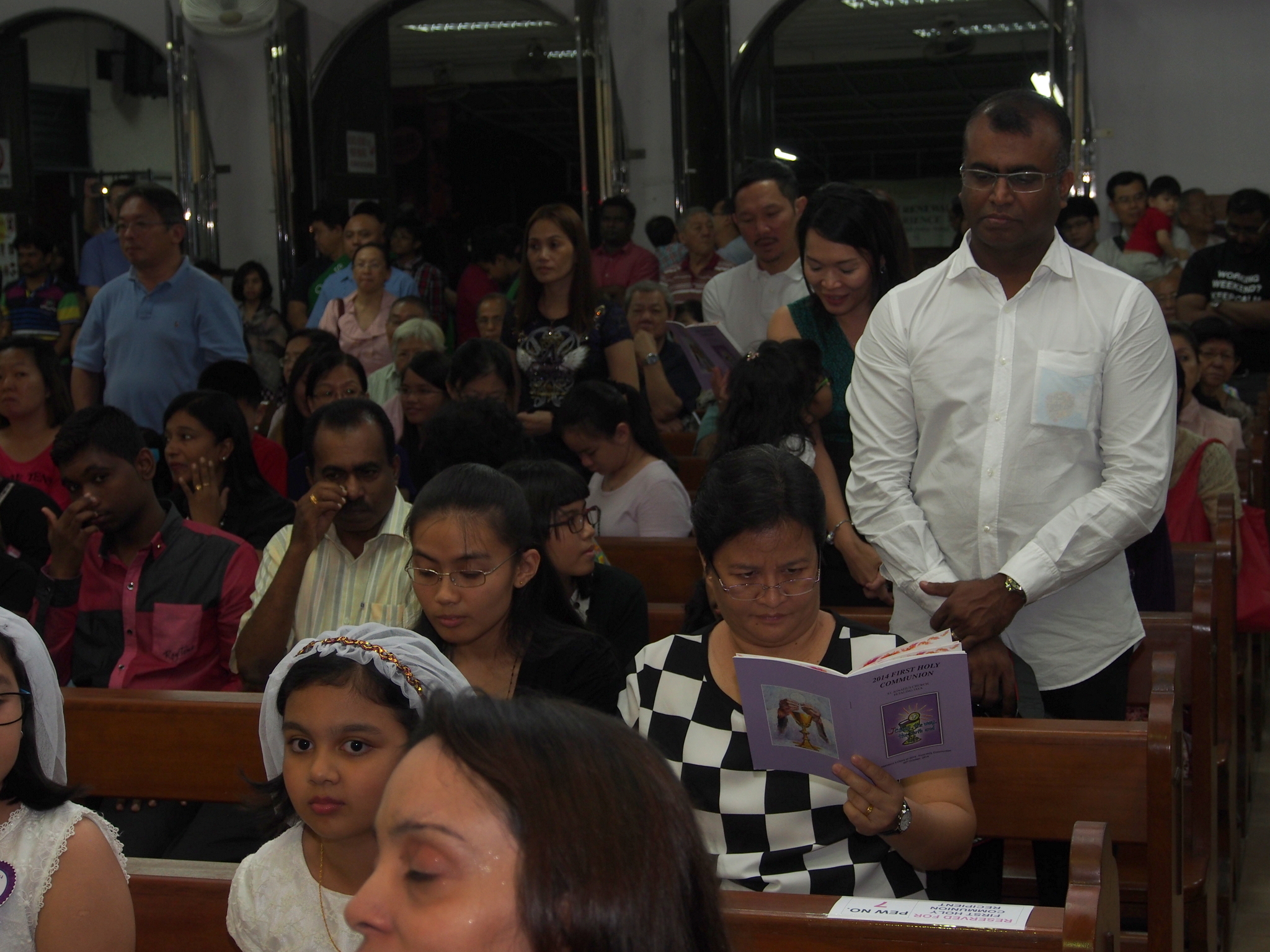 many people are watching another person read in a crowded church