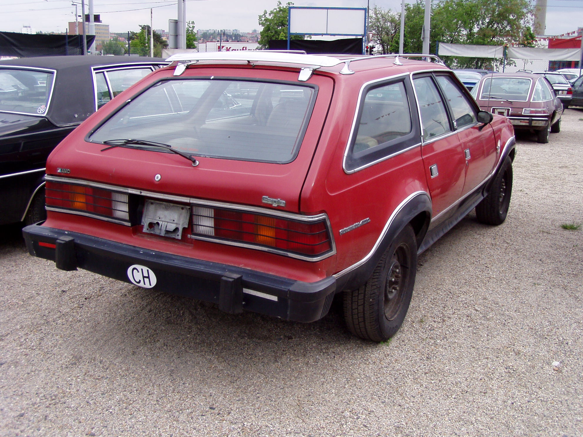 red and black car sitting parked on concrete next to a fence