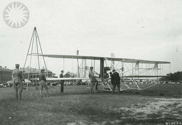 a vintage airplane in a field, some people standing around