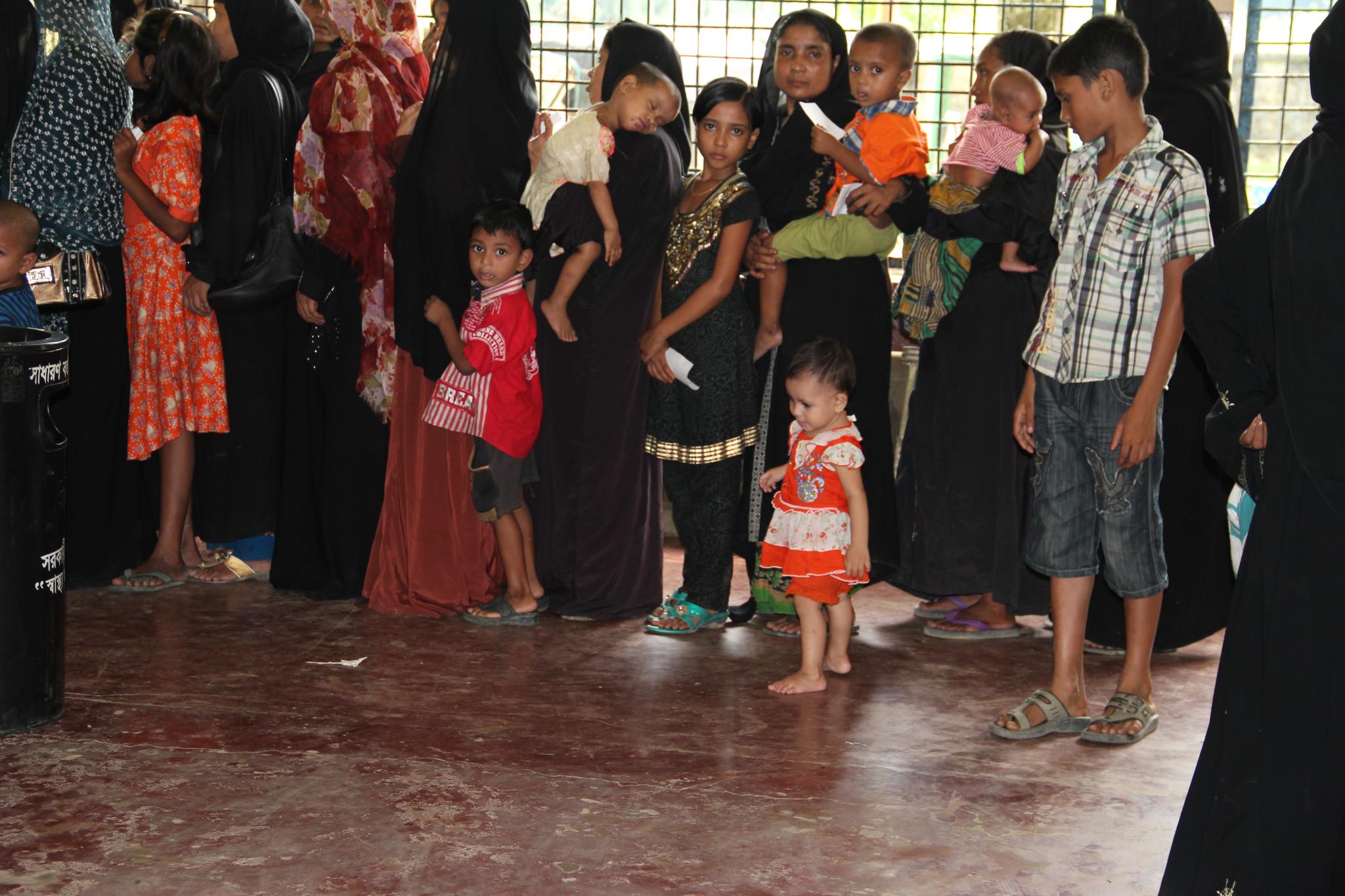 an asian  wearing red looks at a group of adults