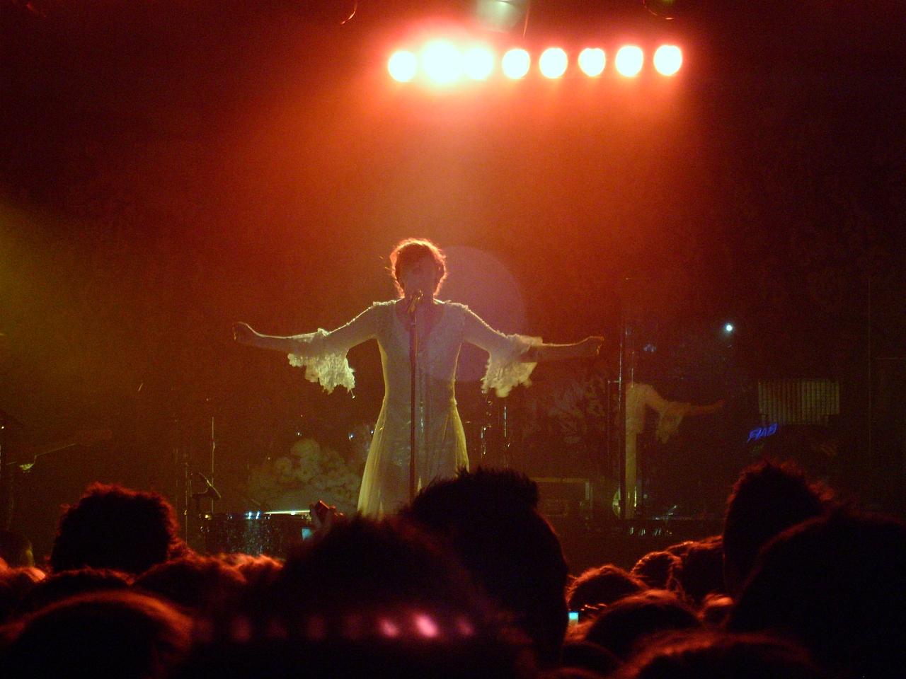 man wearing a dress on stage with hands extended