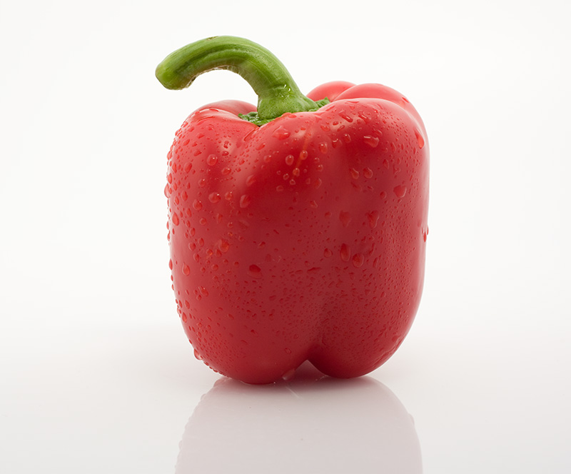 a long pepper on a white surface with drops