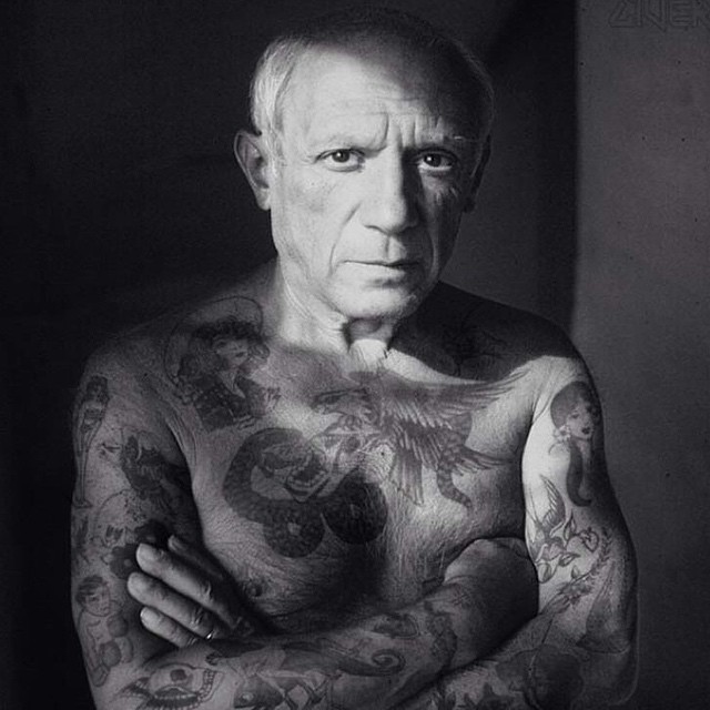 man with arm tattoo posing for camera in black and white