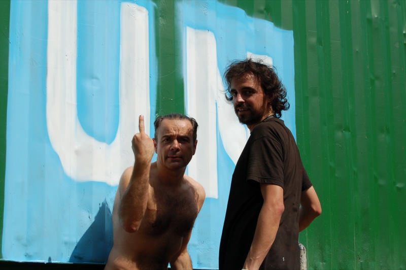 two men standing in front of a blue sign