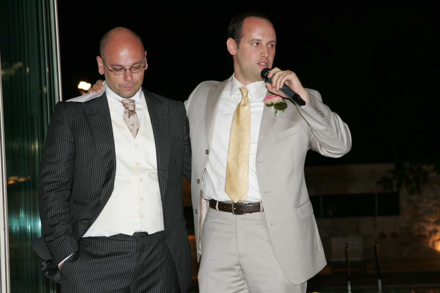 two men are dressed up in suits and tie and holding microphones