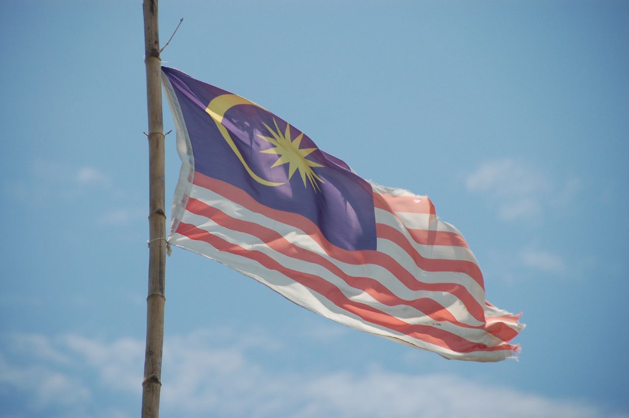 a malaysia american flag flying next to a blue sky