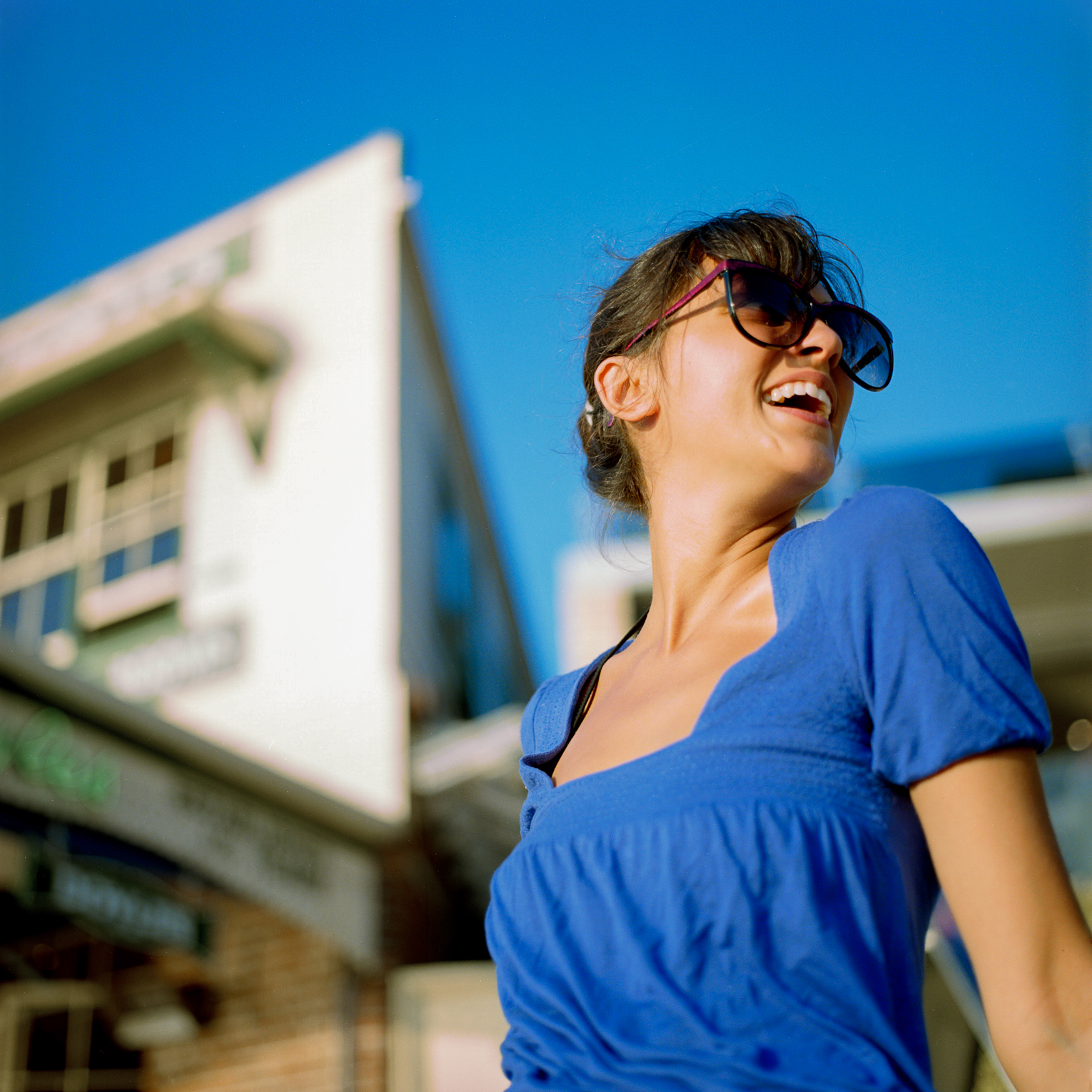 the woman is standing near a building laughing